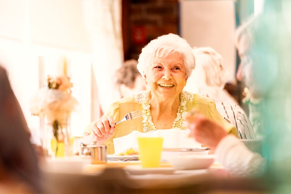 Femme âgée souriante prenant un repas à table