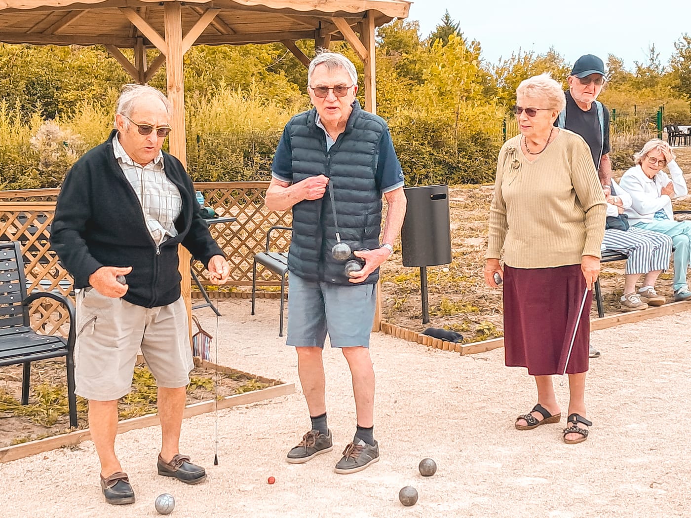 Résidents jouant à la pétanque près d'une pergola au village Sérénya