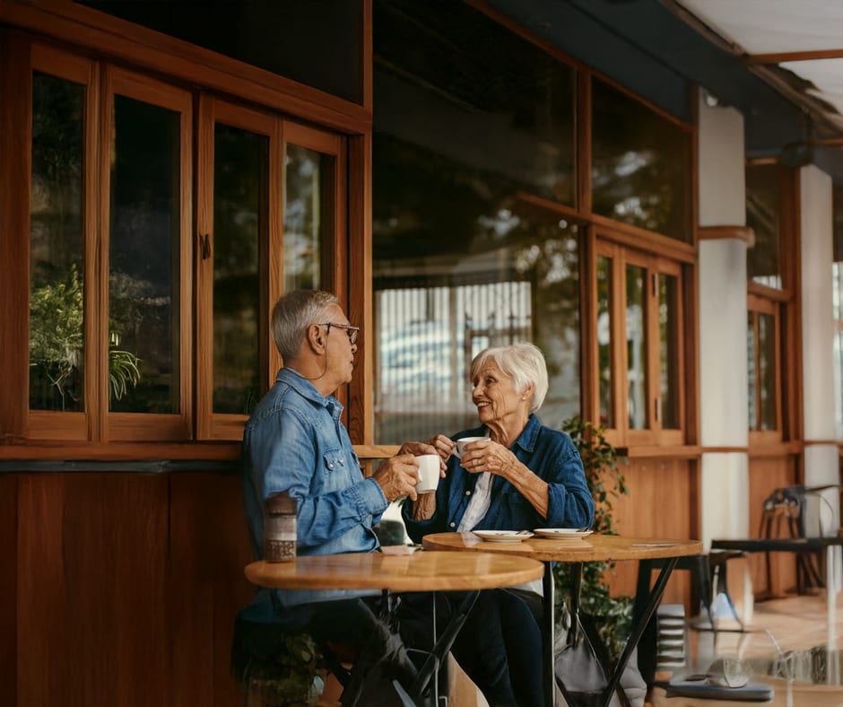 Deux seniors attablés prenant un café sur une terrasse de maison