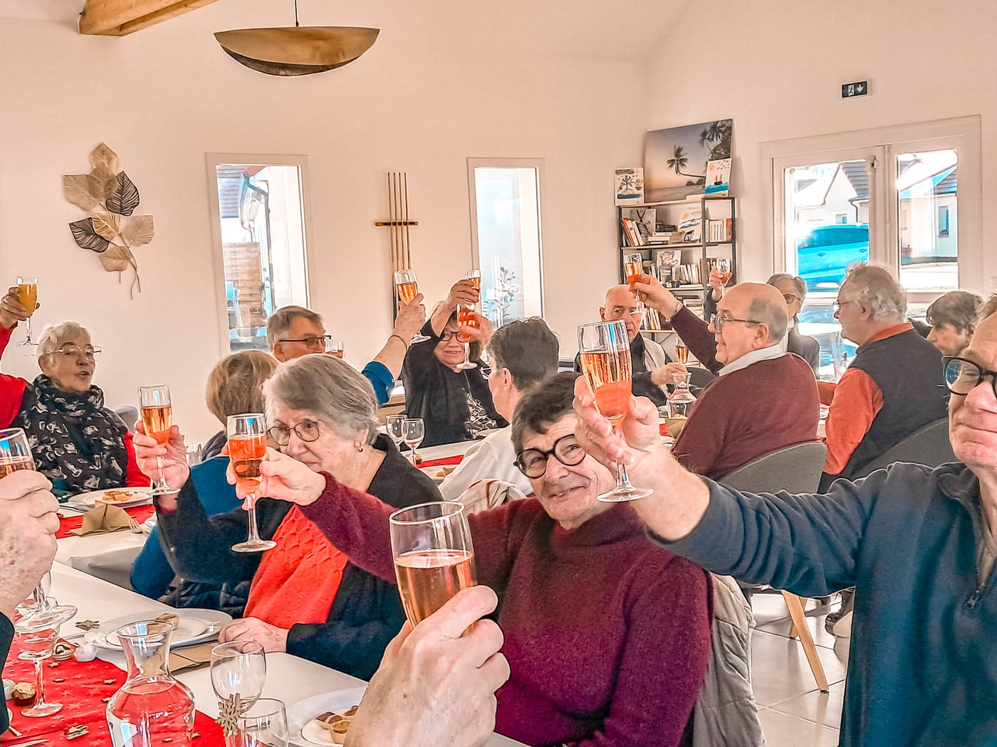 Résidents trinquant lors d'un repas festif au clubhouse du village Sérénya