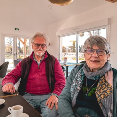 M. et Mme Quillien, résidents du village Sérénya, souriants au clubhouse